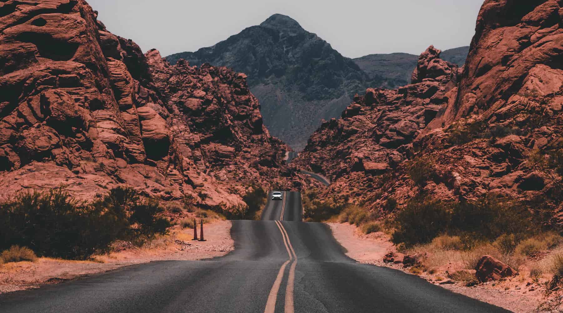 An open road winding through a dramatic red-rock landscape